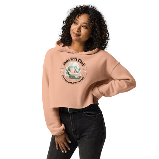 Woman wearing a soft pink cropped hoodie featuring a cozy reading nook and the phrase “Introvert Club – The Moment I Left The Party Vibes”.